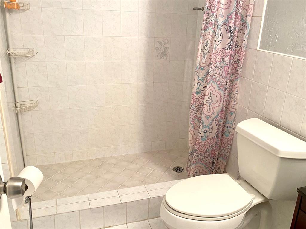 3002 Northeast 5th Terrace, Unit 209B Wilton Manors, FL 33334 - Photo 15 of 25 a white toilet sitting next to a bath tub and a shower