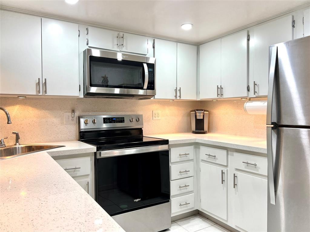 3002 Northeast 5th Terrace, Unit 209B Wilton Manors, FL 33334 - Photo 8 of 25 a kitchen with white cabinets and stainless steel appliances