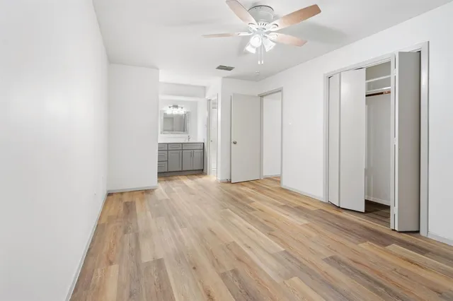 a view of empty room with wooden floor and fan