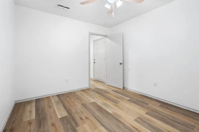 an empty room with a hardwood and ceiling fan