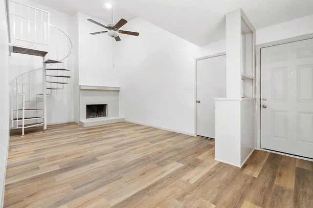 an empty room with wooden floor ceiling fan and windows