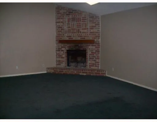 a view of an empty room with wooden floor and a fireplace