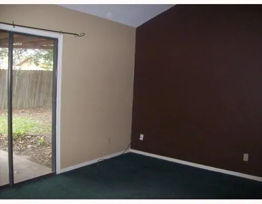 a view of an empty room with wooden floor and windows