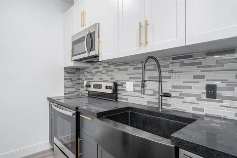 a kitchen with granite countertop a sink stainless steel appliances and cabinets