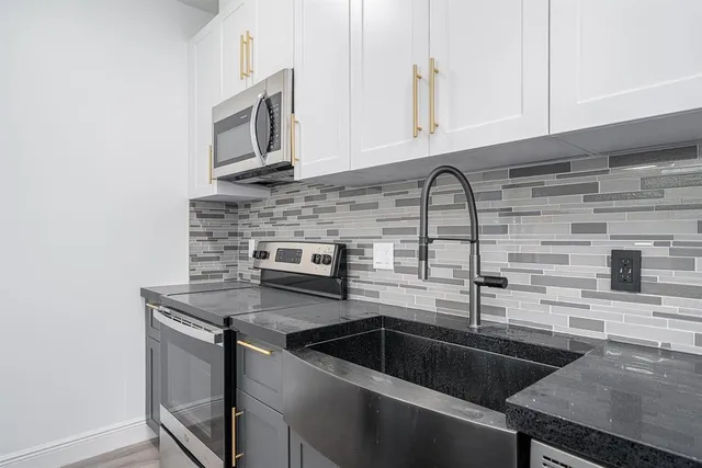 a kitchen with granite countertop a sink stainless steel appliances and cabinets