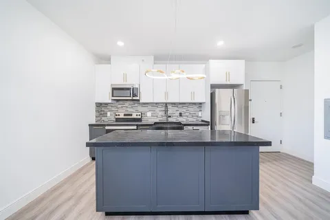 a kitchen with kitchen island stainless steel appliances a sink stove and refrigerator