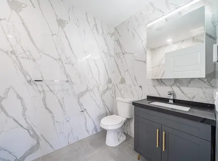 a bathroom with a granite countertop sink toilet and a mirror