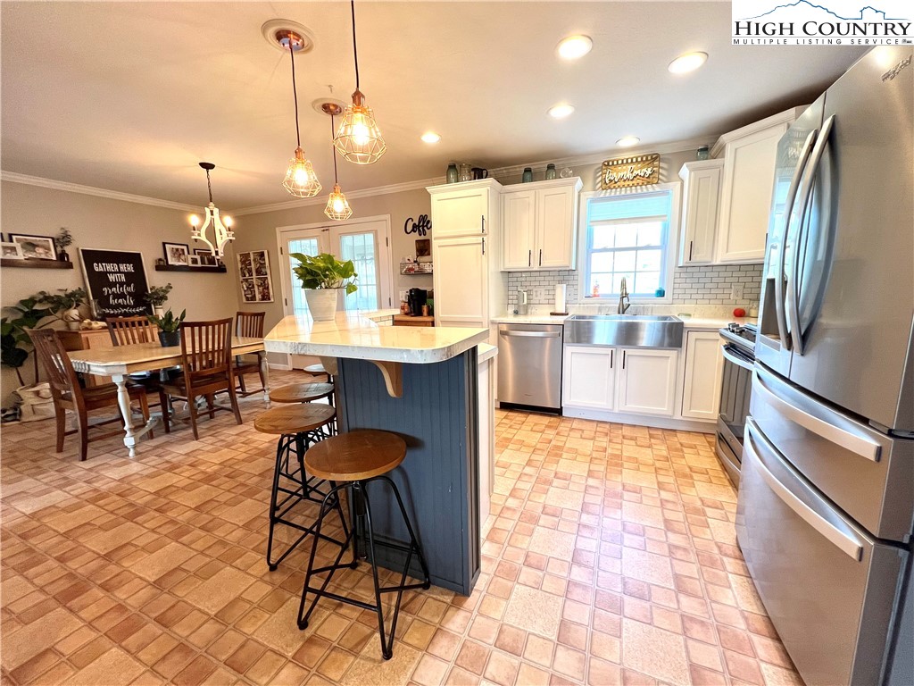 1534 Longhope Road Todd, NC 28684 - Photo 9 of 35 a open kitchen with stainless steel appliances granite countertop a stove a sink dishwasher a dining table and chairs with wooden floor