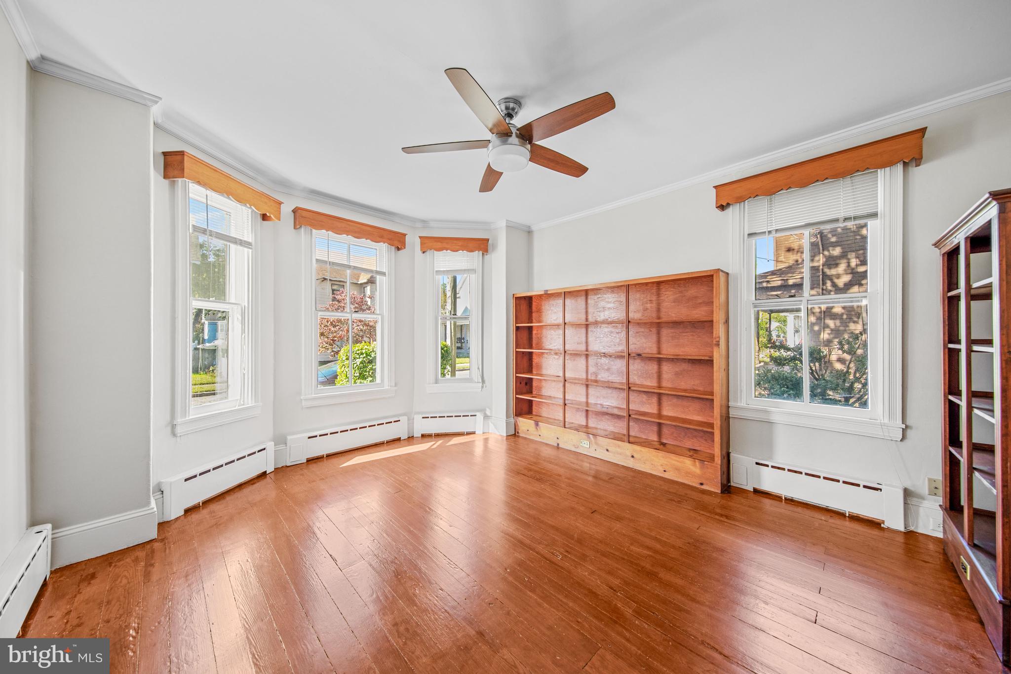 817 Locust Street Cambridge, MD 21613 - Photo 9 of 44 an empty room with wooden floor fan and windows