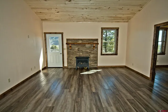 an empty room with wooden floor fireplace and windows