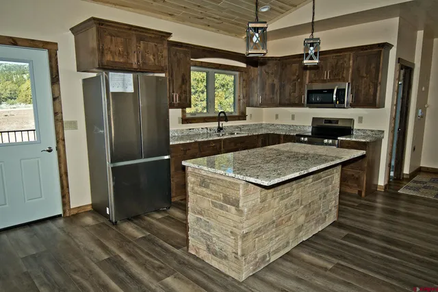 a kitchen with stainless steel appliances granite countertop a sink stove and refrigerator