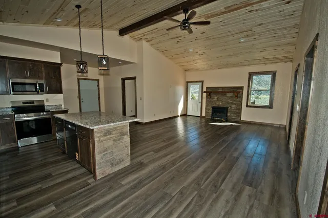 a large kitchen with stainless steel appliances granite countertop a stove and a wooden floors