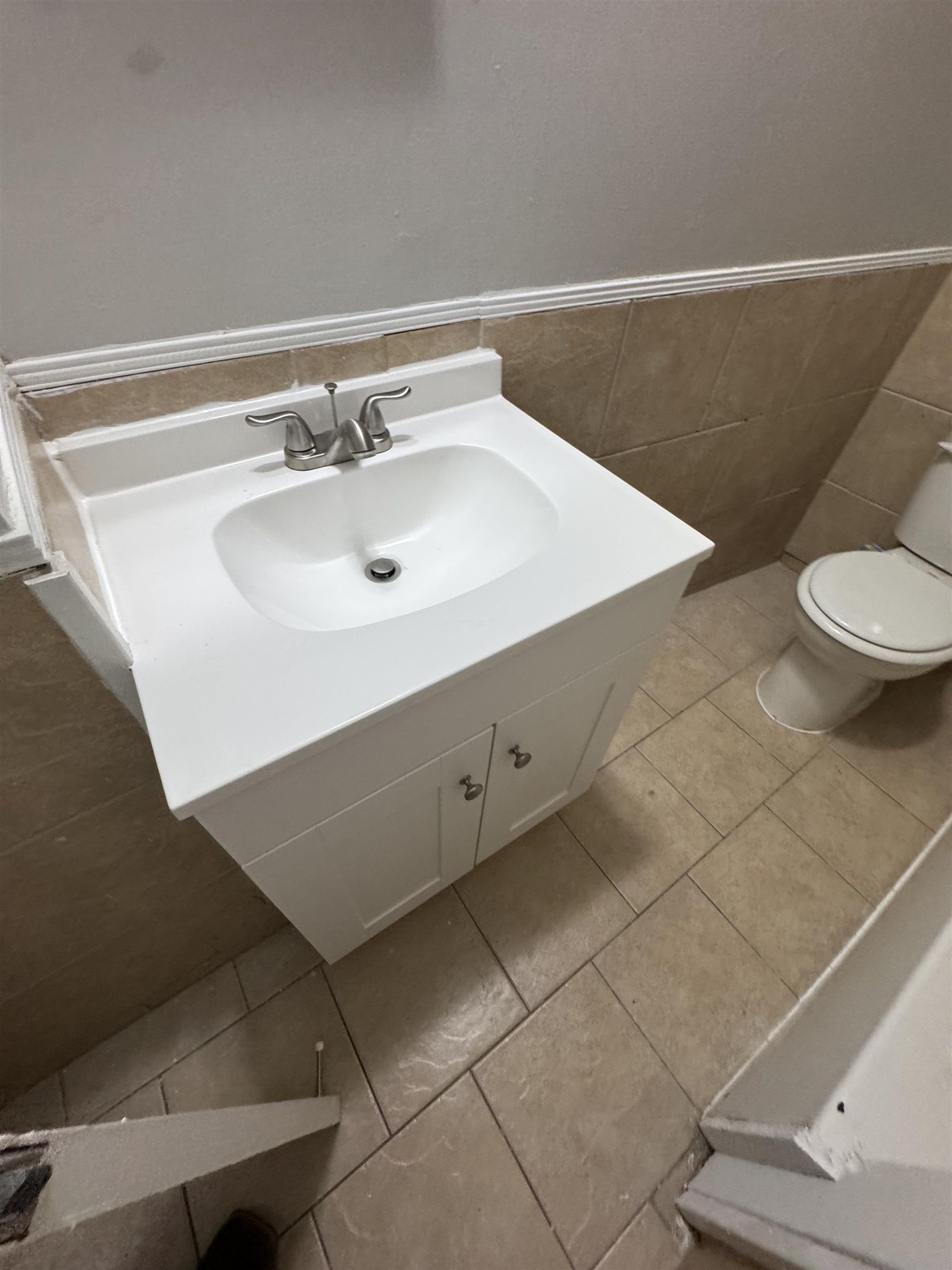 4173 Cottonwood Road Memphis, TN 38118 - Photo 12 of 13 Bathroom featuring vanity, light tile patterned floors, tile walls, and a wainscoted wall