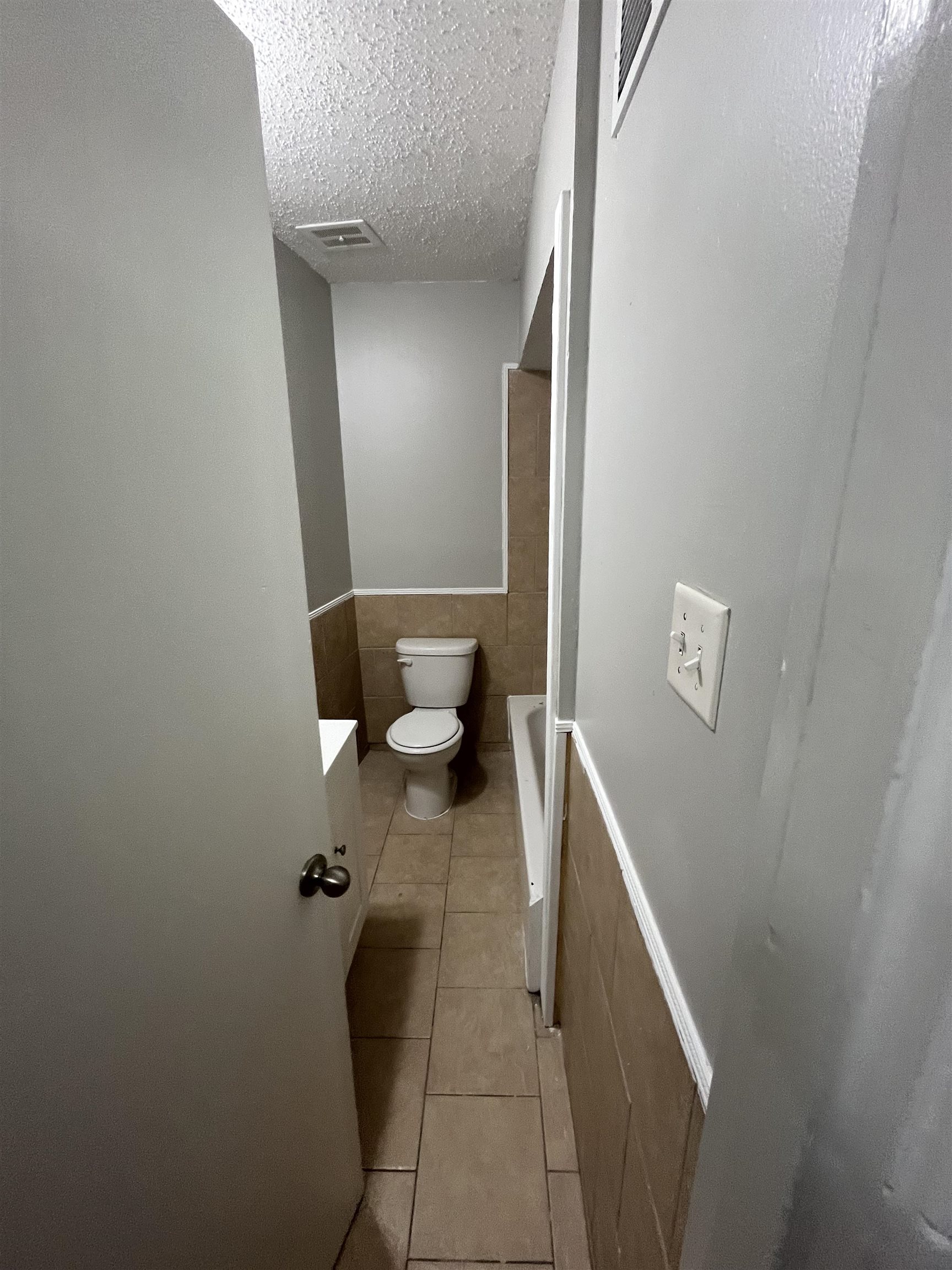 4173 Cottonwood Road Memphis, TN 38118 - Photo 10 of 13 Full bath featuring tile walls, light tile patterned floors, wainscoting, vanity, and a textured ceiling