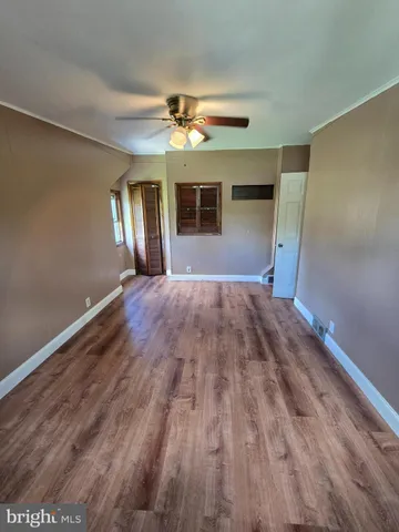 a view of empty room with wooden floor and fan