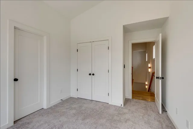 a view of an empty room with closet and mirror