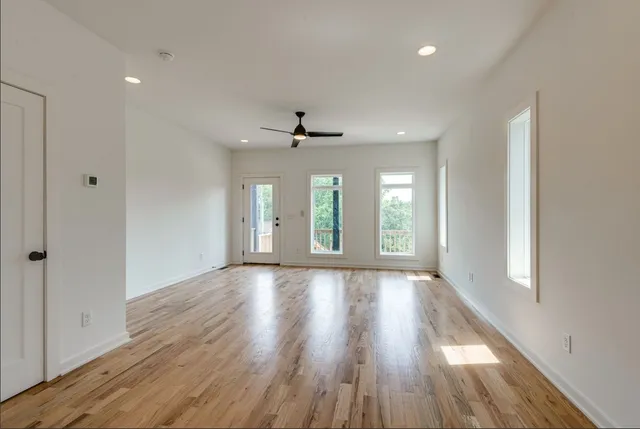 a view of an empty room with wooden floor and a window