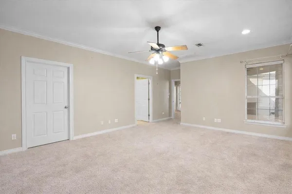 an empty room with chandelier fan and windows
