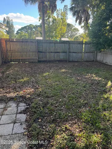 a view of a backyard with a large tree and wooden fence