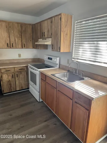a kitchen with stainless steel appliances granite countertop a sink a stove and a wooden cabinets