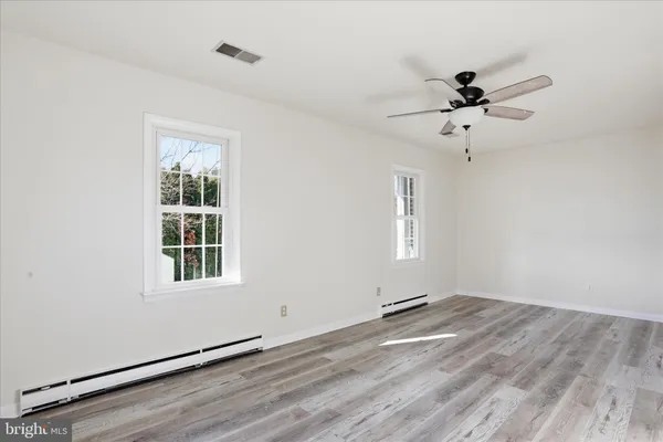 a view of empty room with wooden floor and fan