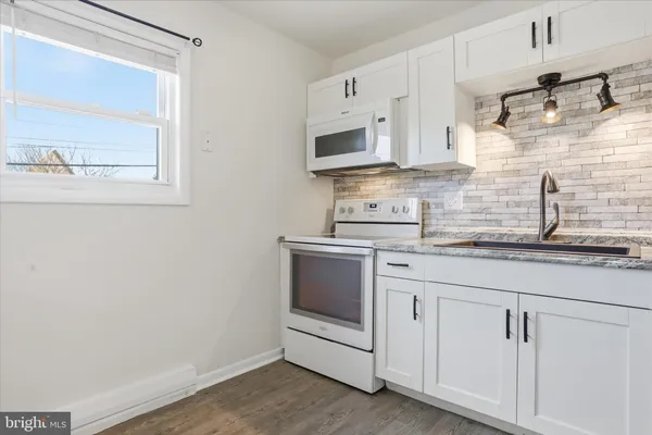 a kitchen with stainless steel appliances granite countertop white cabinets and window