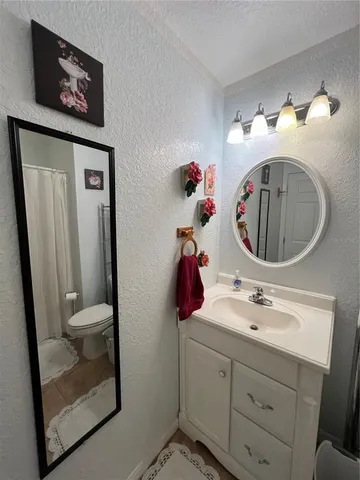 a bathroom with a toilet sink vanity and mirror