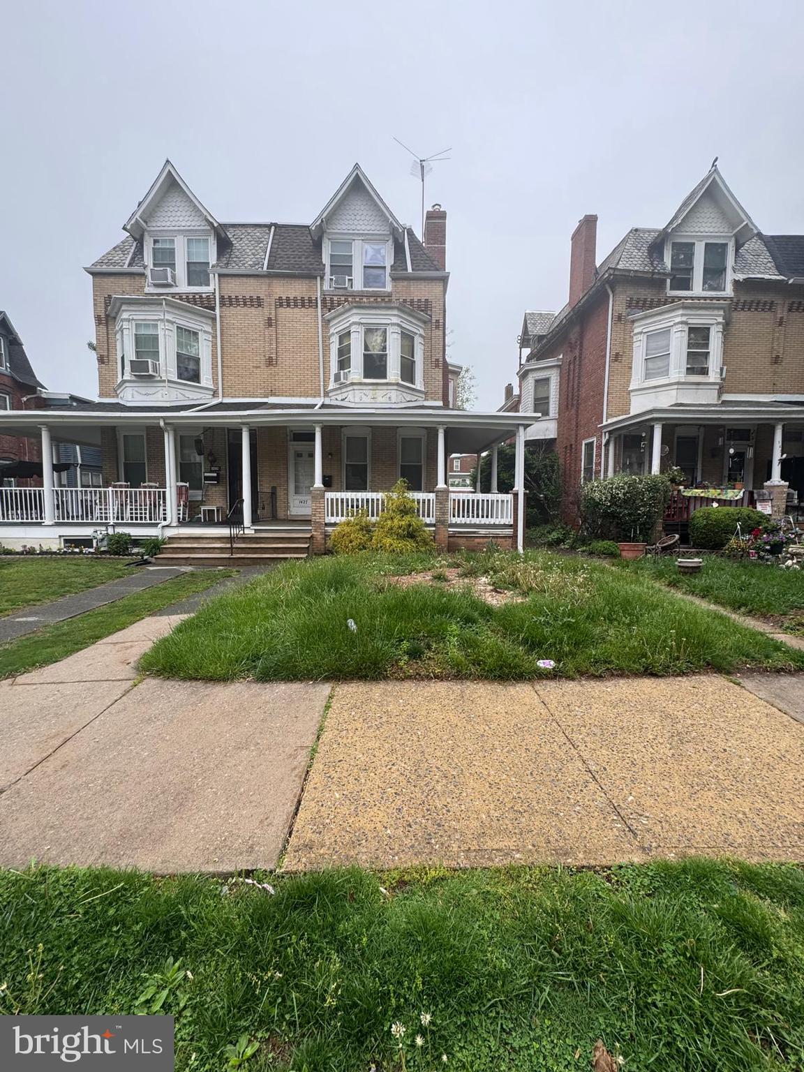 a front view of a building with a yard and potted plants