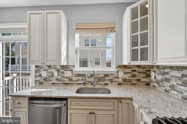 a kitchen with granite countertop a sink and a white wooden cabinets