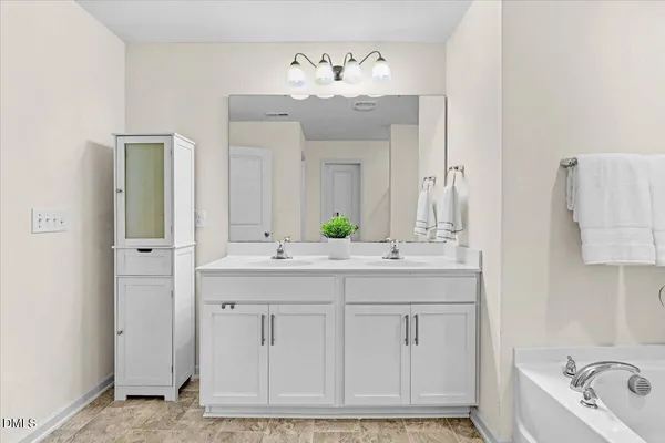 a bathroom with a double vanity sink mirror and bathtub