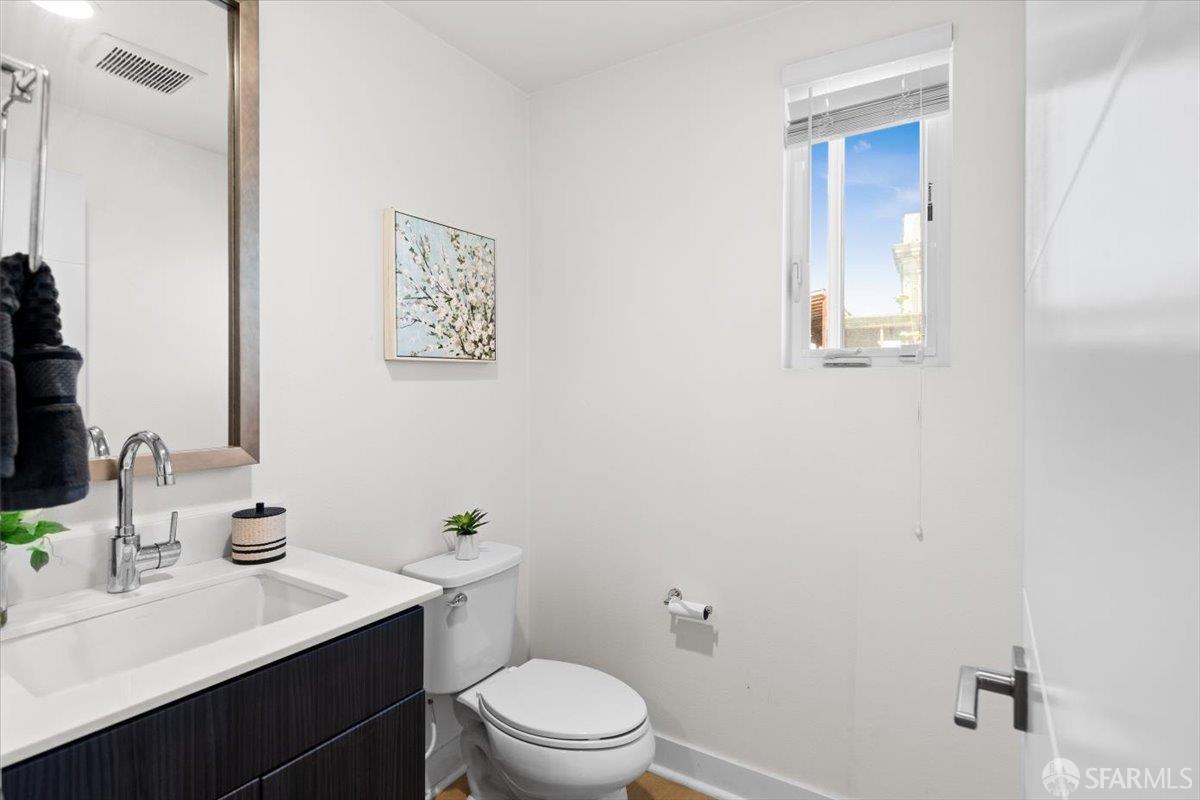 1807 16th Street Oakland, CA 94607 - Photo 12 of 45 a bathroom with a toilet a sink a mirror and vanity