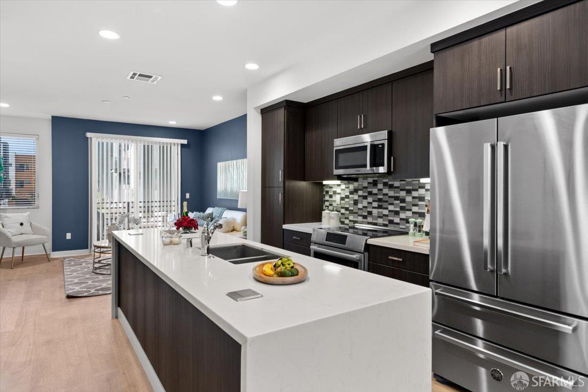1807 16th Street Oakland, CA 94607 - Photo 9 of 45 a kitchen with stainless steel appliances kitchen island granite countertop a refrigerator a stove and a sink with wooden floor