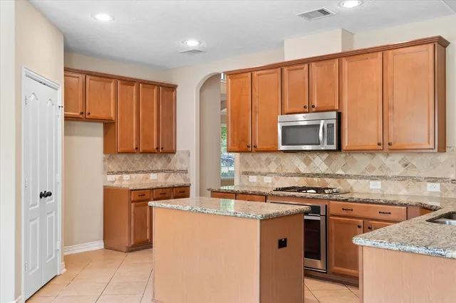 a kitchen with stainless steel appliances granite countertop a stove a sink and a microwave