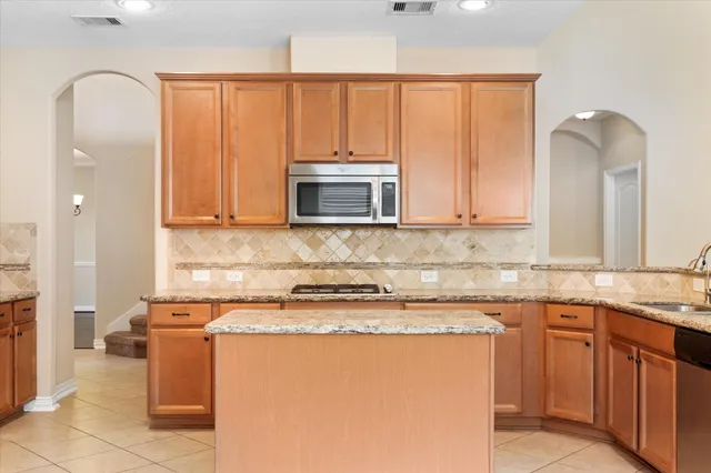a kitchen with stainless steel appliances granite countertop a stove a sink and a microwave