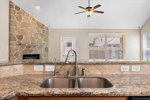 a kitchen with granite countertop a sink a counter top space cabinets and stainless steel appliances