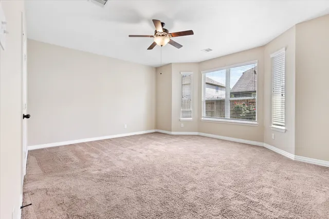 an empty room with windows and ceiling fan