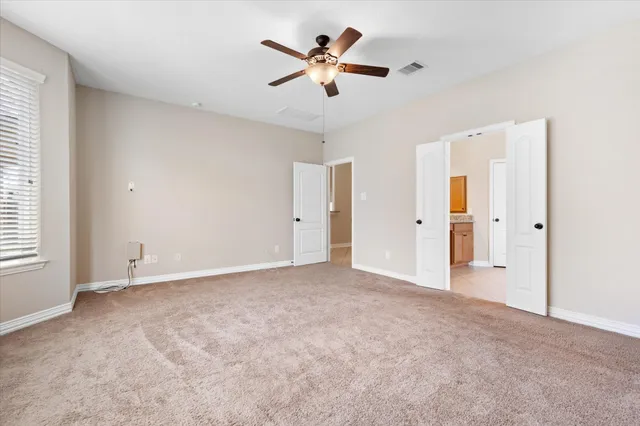 an empty room with closet and a ceiling fan