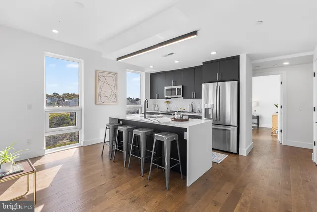 a kitchen with stainless steel appliances a dining table chairs refrigerator and microwave