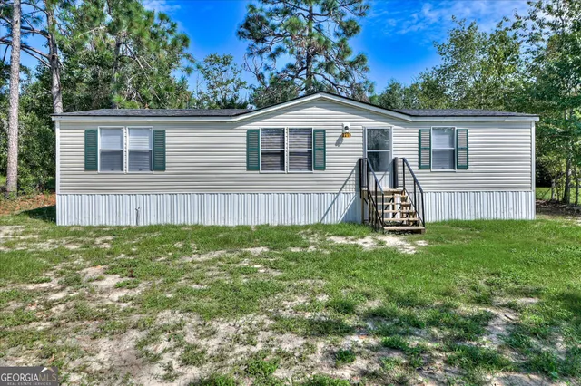 a view of a house with a yard and a large tree