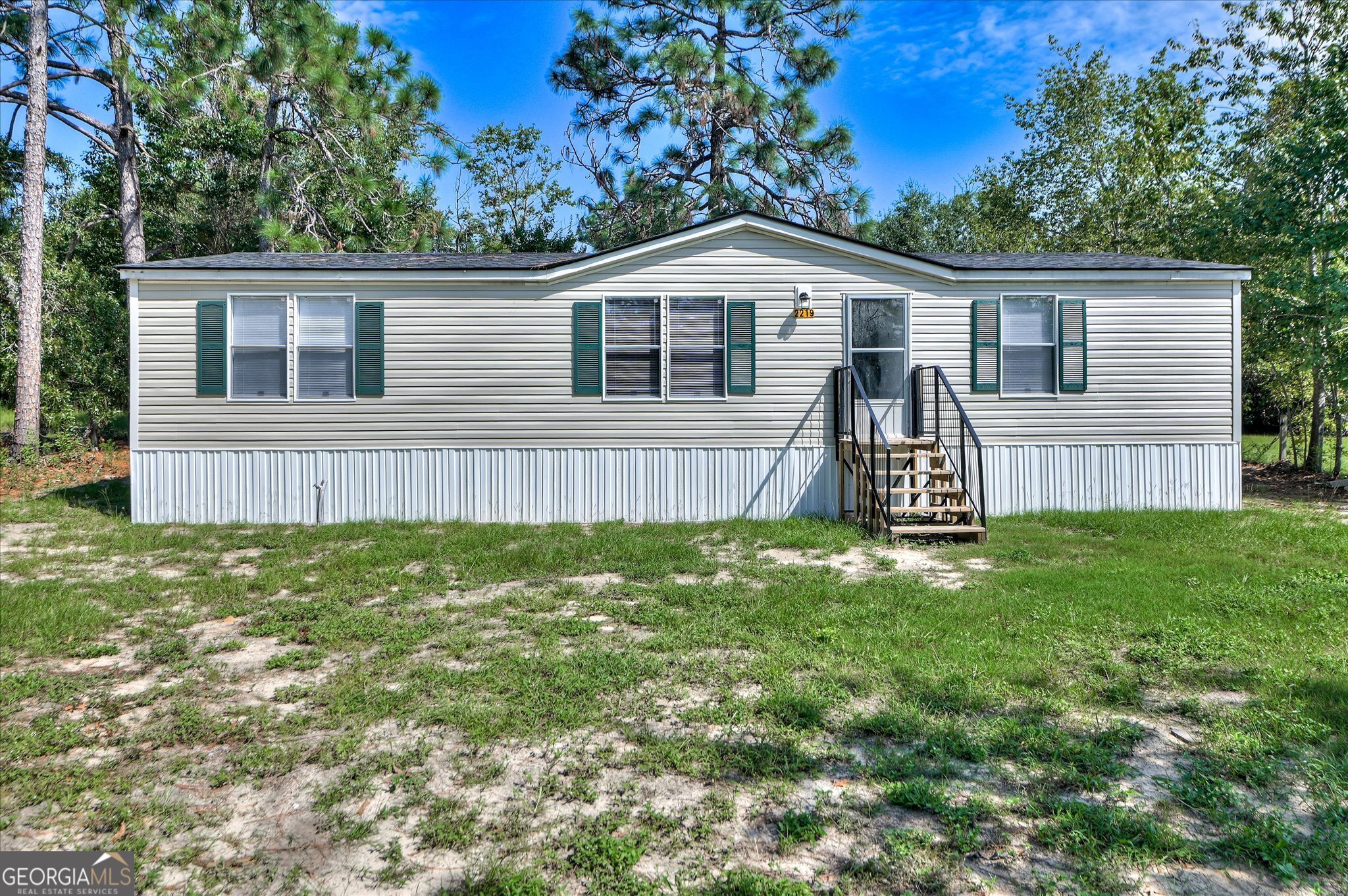 a view of a house with a yard and a large tree