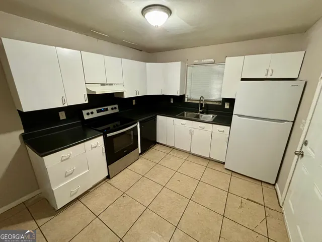 a kitchen with granite countertop white cabinets and white appliances