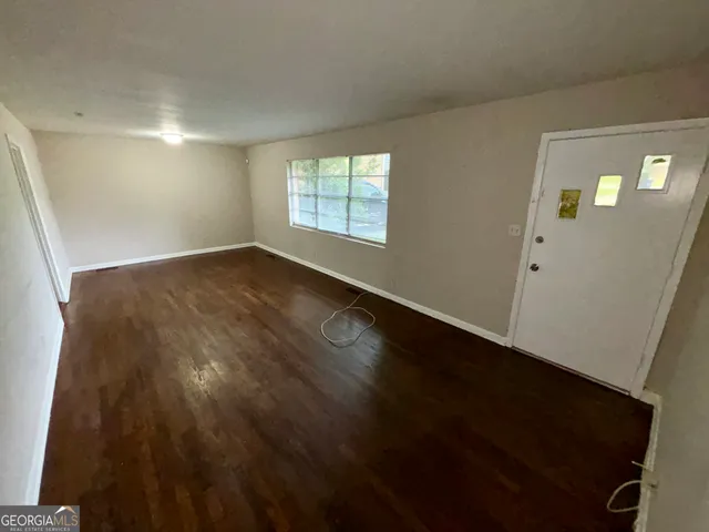 a view of an empty room with wooden floor and a window