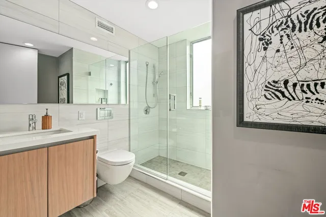 a bathroom with a shower sink vanity mirror and toilet