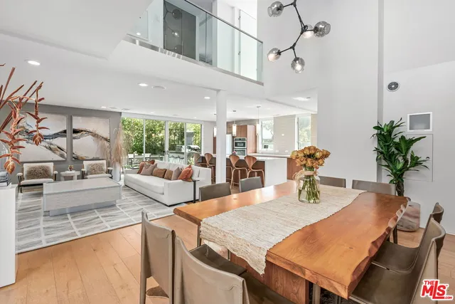 a view of a dining room and livingroom with furniture wooden floor a potted plant and a chandelier
