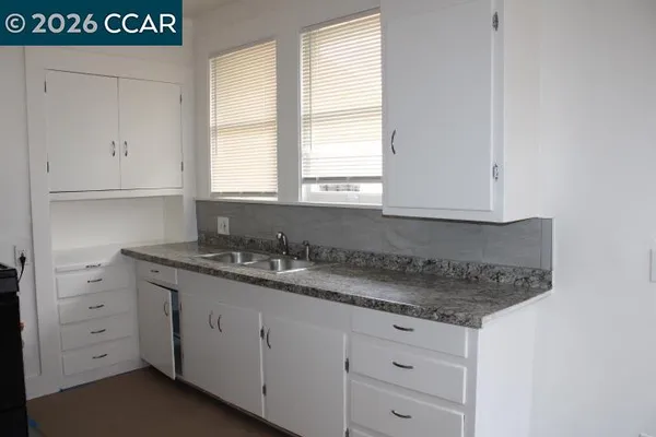 a kitchen with granite countertop white cabinets and a sink