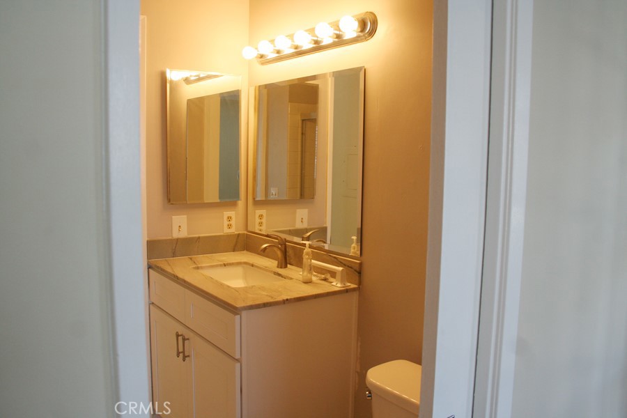 17140 Bluewater Lane, Unit 154 Huntington Beach, CA 92649 - Photo 14 of 28 a bathroom with a granite countertop sink and a mirror