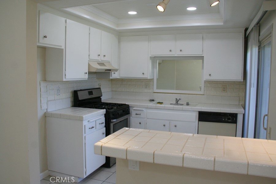 17140 Bluewater Lane, Unit 154 Huntington Beach, CA 92649 - Photo 17 of 28 a kitchen with a white stove top oven sink and cabinets