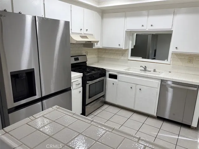 a kitchen with stainless steel appliances a refrigerator sink and microwave
