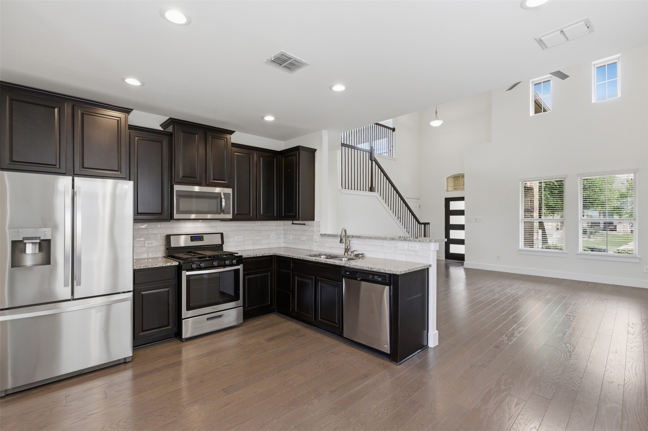 2004 Garretts Way Manchaca, TX 78652 - Photo 13 of 37 Kitchen with stainless steel appliances, dark wood-style flooring, a peninsula, light stone counters, and backsplash
