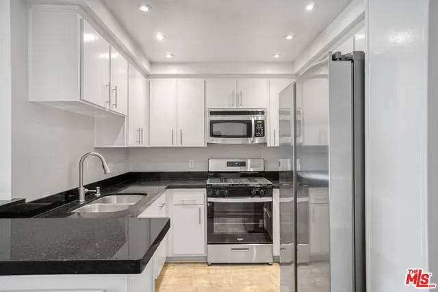 a kitchen with granite countertop white cabinets and stainless steel appliances